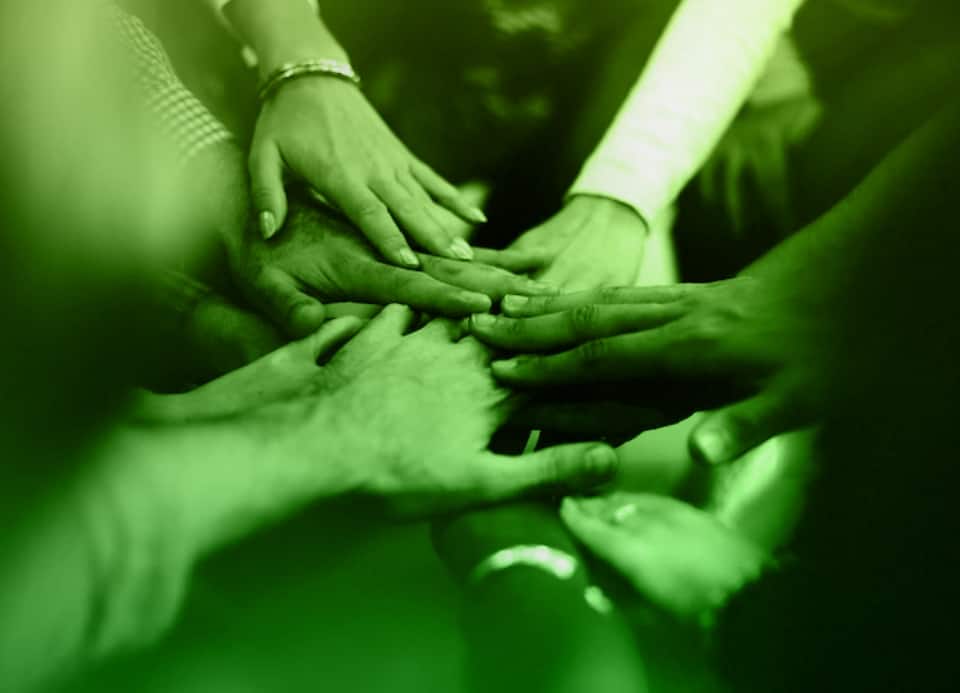 Team members putting hands in the middle signifying working together